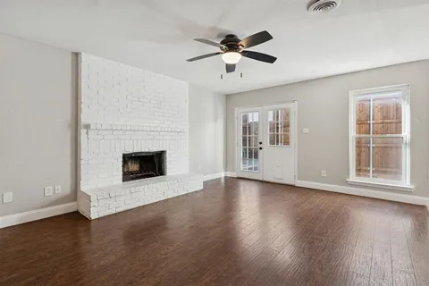 a view of an empty room with wooden floor fireplace and a window