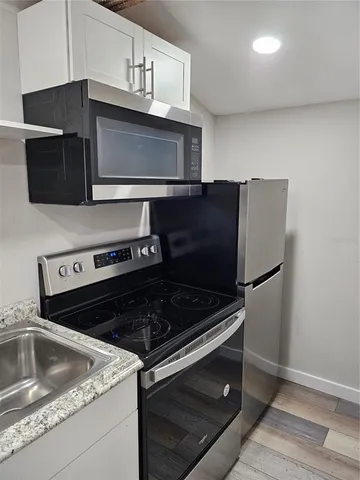 a kitchen with granite countertop white cabinets and stainless steel appliances