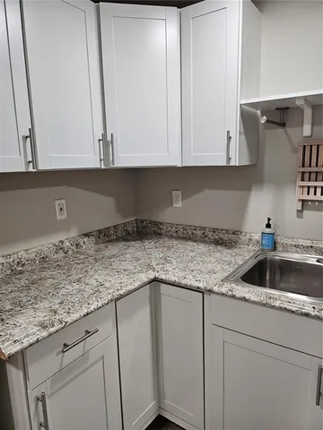 a kitchen with granite countertop white cabinets and sink