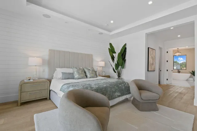 a view of a hallway with wooden floor and a bathroom