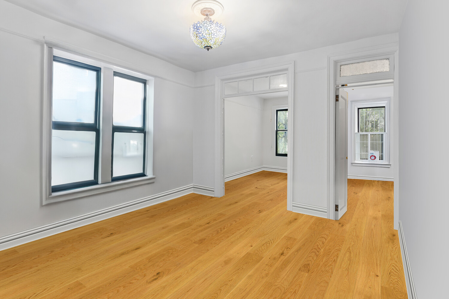 214 Bradhurst Avenue, Unit 4 Manhattan, NY 10039 - Photo 4 of 11 a view of an empty room with window and wooden floor