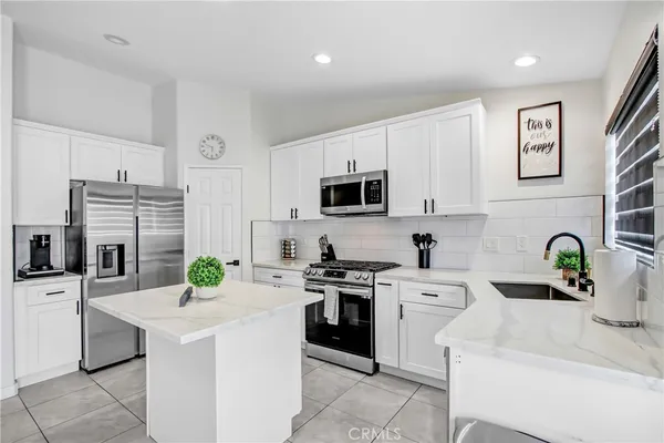 a kitchen with white cabinets and appliances