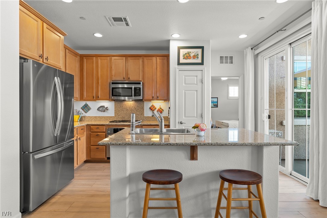 1795 Wind Ranch Road, Unit C Reno, NV 89521 - Photo 9 of 17 a kitchen with stainless steel appliances granite countertop a refrigerator a sink a stove a dining table and chairs