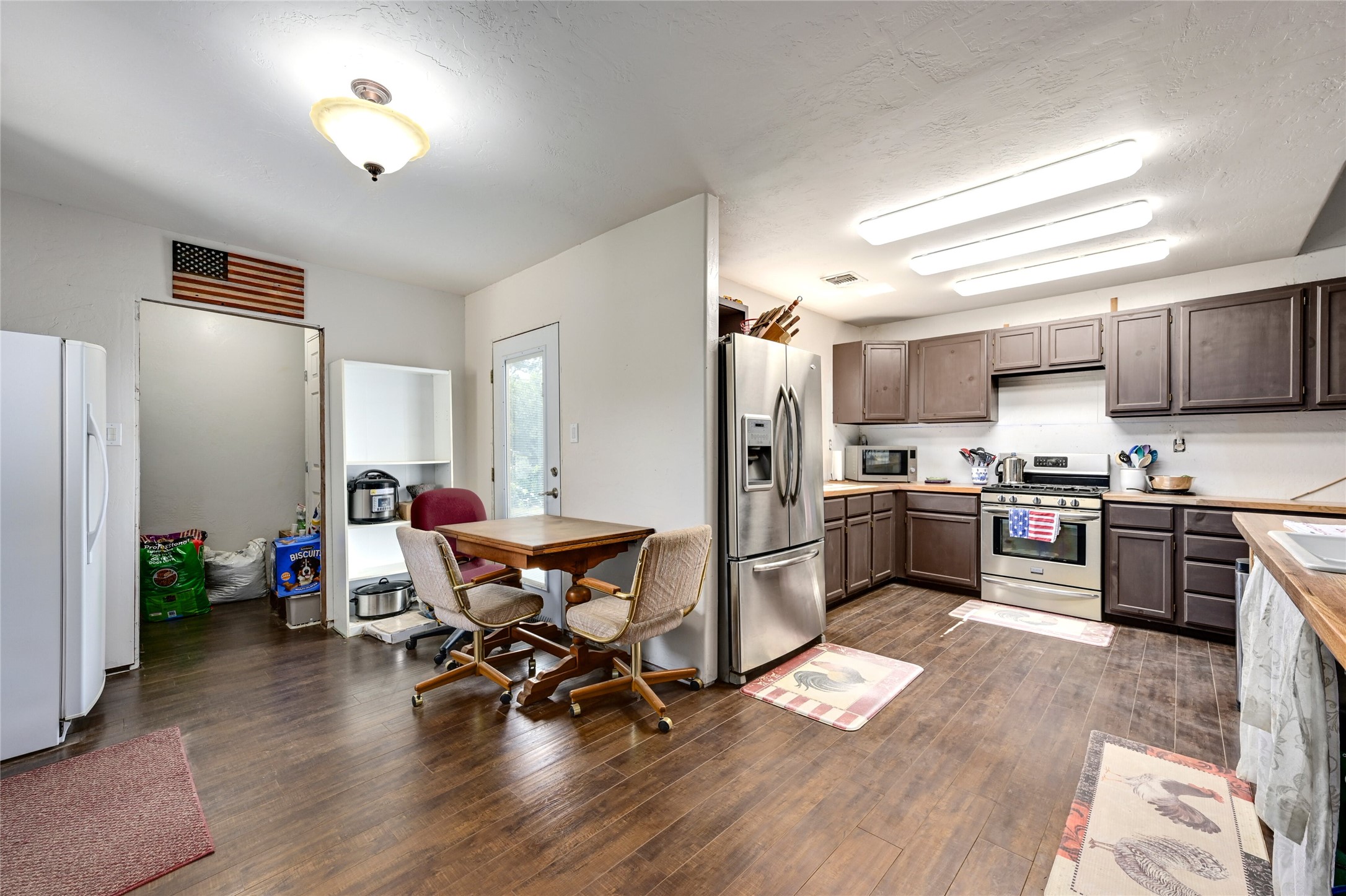 681 County Road 474 Elgin, TX 78621 - Photo 8 of 37 a kitchen with a refrigerator a stove top oven a sink dishwasher and dining table with wooden floor