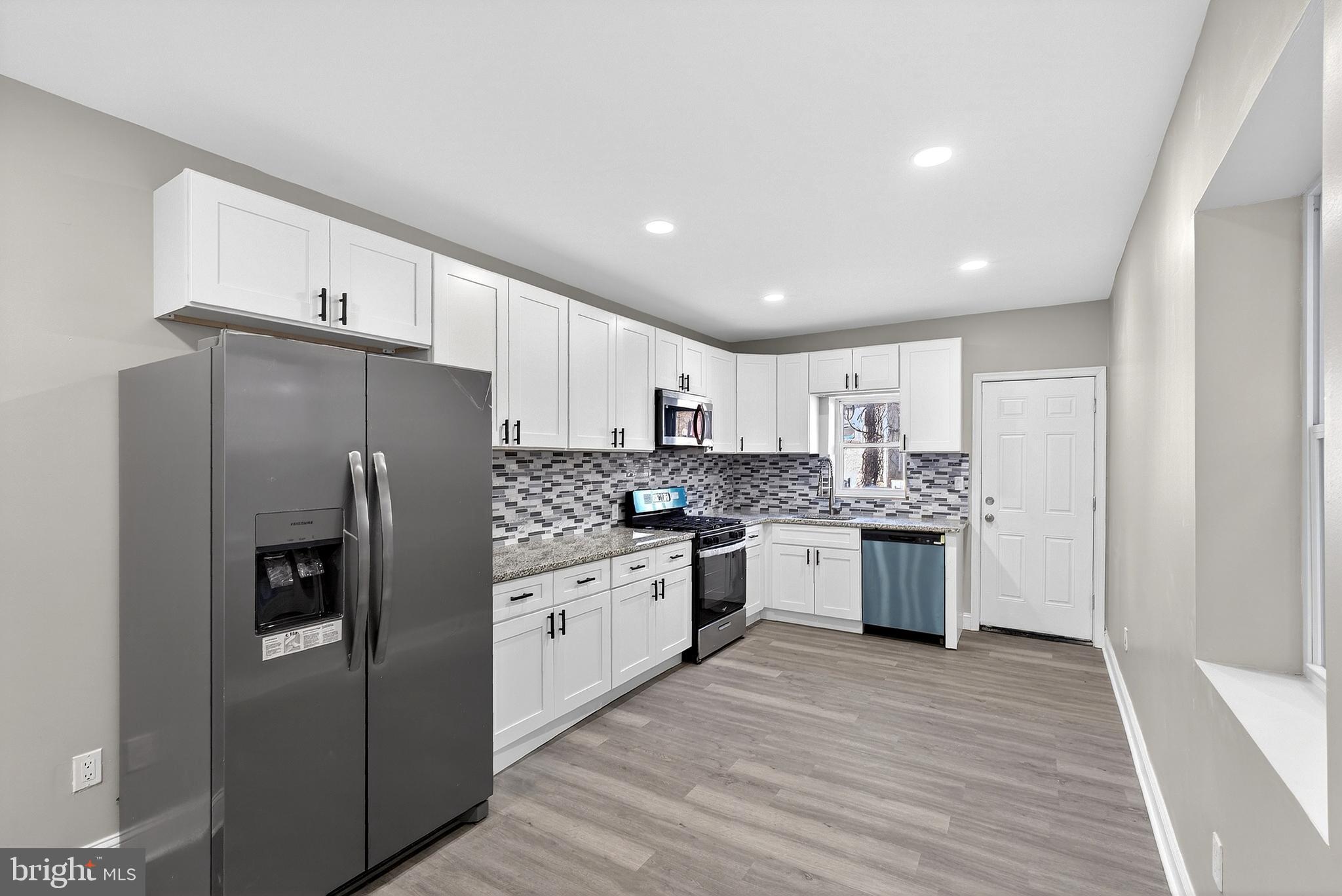 5443 Irving Street Philadelphia, PA 19139 - Photo 13 of 50 a kitchen with stainless steel appliances granite countertop a refrigerator sink and white cabinets
