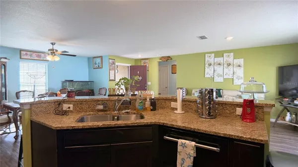a view of kitchen island a sink wooden floor and living room