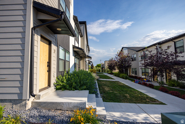 220 Spring Creek Parkway Providence, UT 84332 - Photo 6 of 26 Contemporary townhome exterior featuring light gray siding and a natural wood-finish entry door