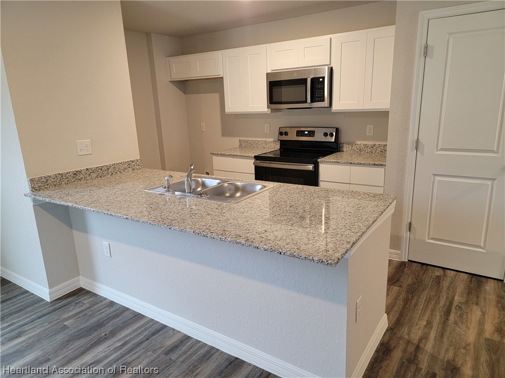 1389 Stone Circle Sebring, FL 33870 - Photo 5 of 39 a kitchen with granite countertop cabinets and wooden floor