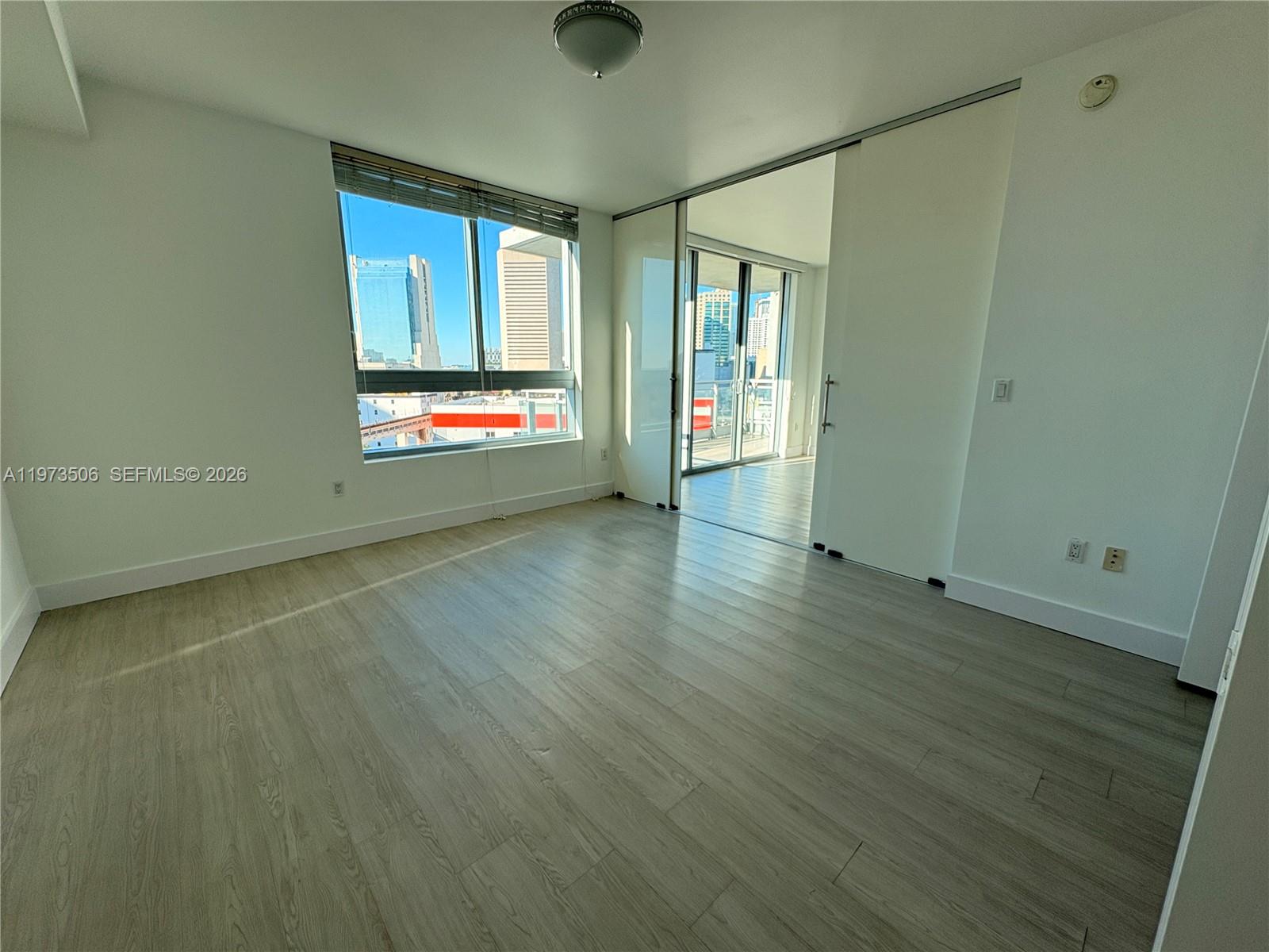 90 Southwest 3rd Street, Unit 1205 Miami, FL 33130 - Photo 13 of 41 an empty room with wooden floor and windows