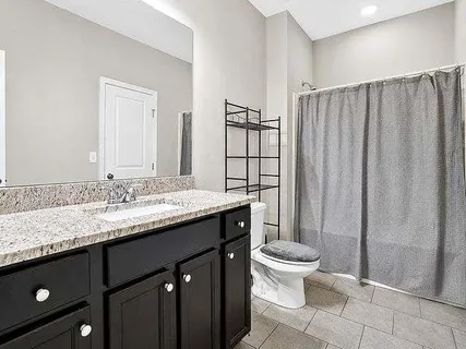 a bathroom with a granite countertop sink toilet and shower