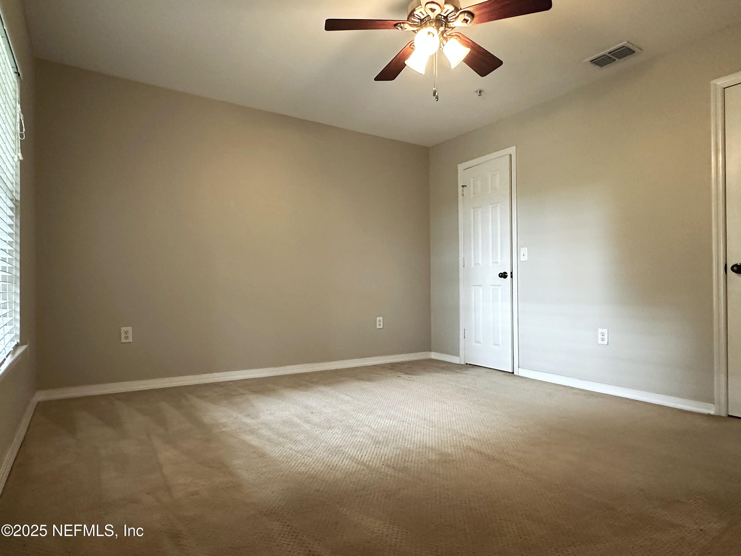 7800 Point Meadows Drive, Unit 631 Jacksonville, FL 32256 - Photo 23 of 26 an empty room with a chandelier fan and windows