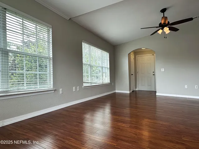 a view of an empty room with a window and wooden floor