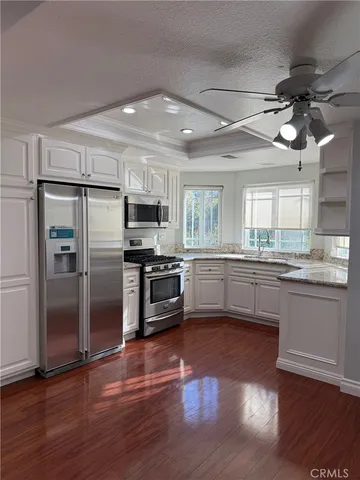 a kitchen with granite countertop a refrigerator oven a sink dishwasher and wooden floor