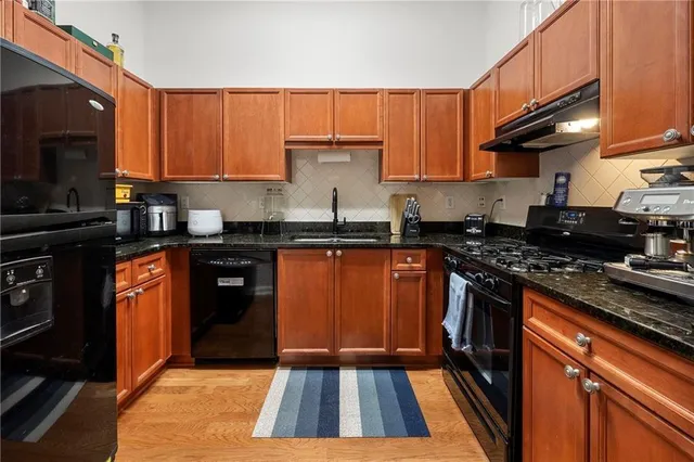 a kitchen with stainless steel appliances a stove a sink dishwasher and cabinets with wooden floor