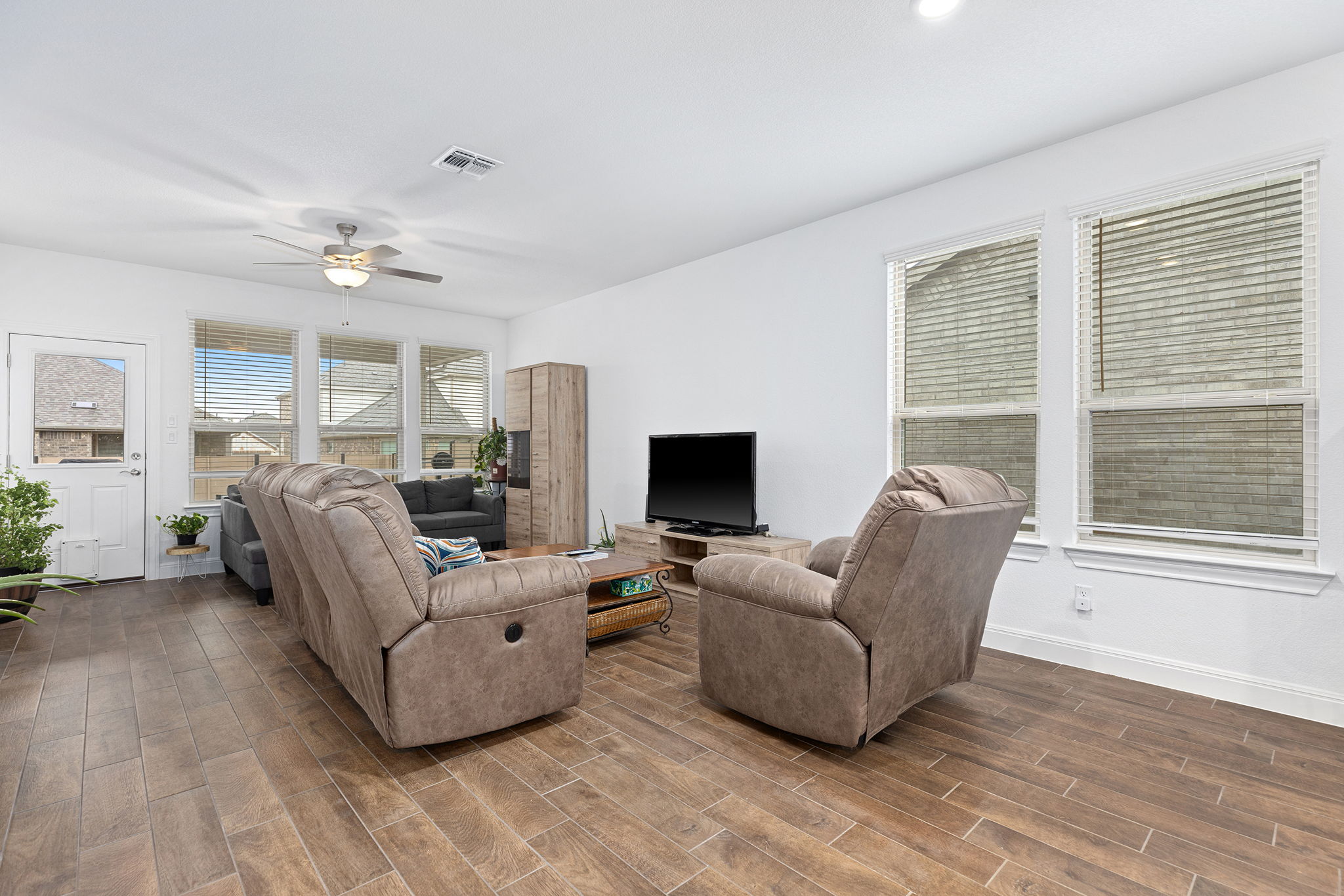116 Raleigh Drive Georgetown, TX 78633 - Photo 9 of 28 Rich wood-look flooring grounds this open living area, complemented by natural light and a modern ceiling fan.