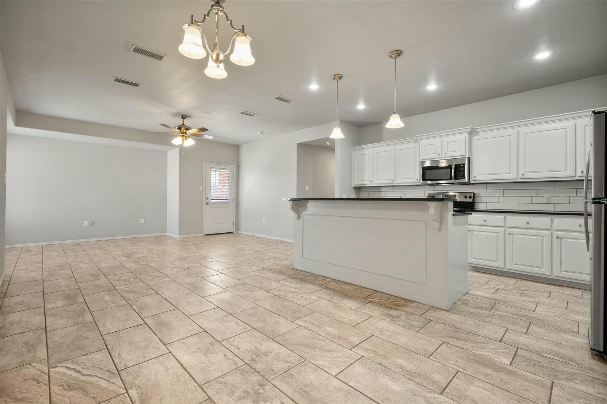 2619 113th Street Lubbock, TX 79423 - Photo 11 of 31 a kitchen with stainless steel appliances granite countertop a stove top oven a sink a counter top space cabinets and a window