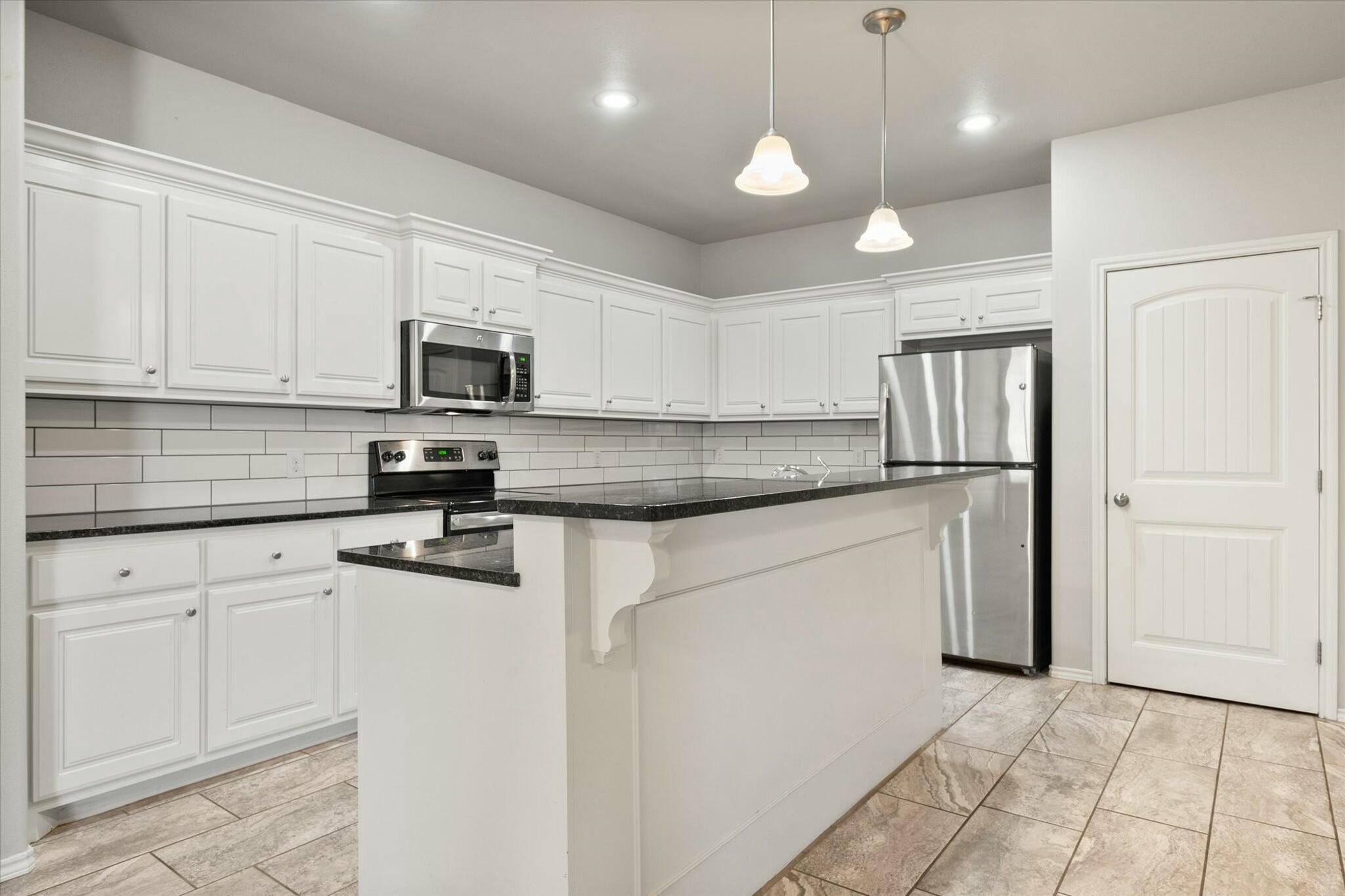 2619 113th Street Lubbock, TX 79423 - Photo 13 of 31 a kitchen with granite countertop white cabinets and stainless steel appliances