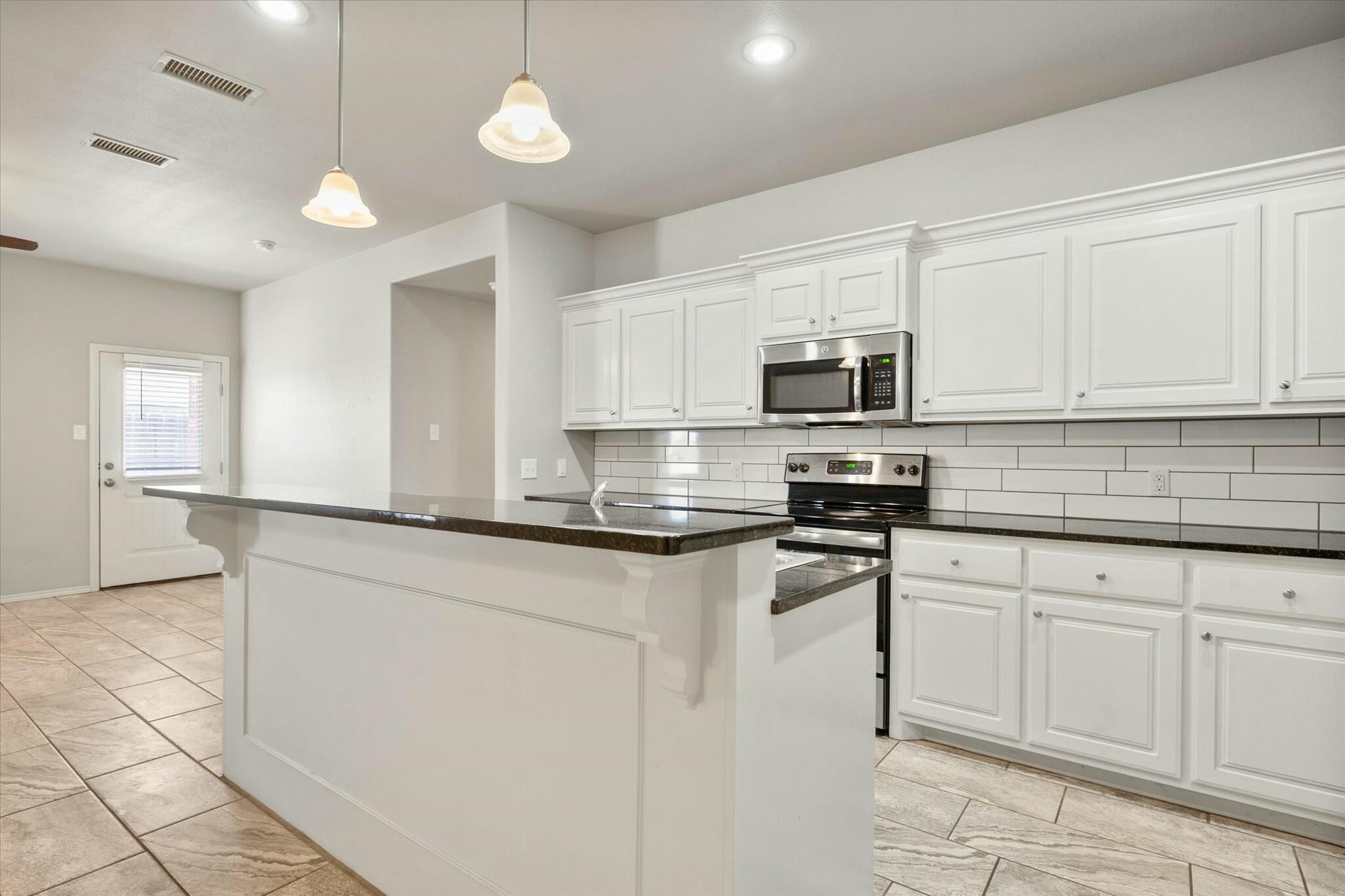 2619 113th Street Lubbock, TX 79423 - Photo 15 of 31 a kitchen with stainless steel appliances granite countertop a stove a sink and a microwave