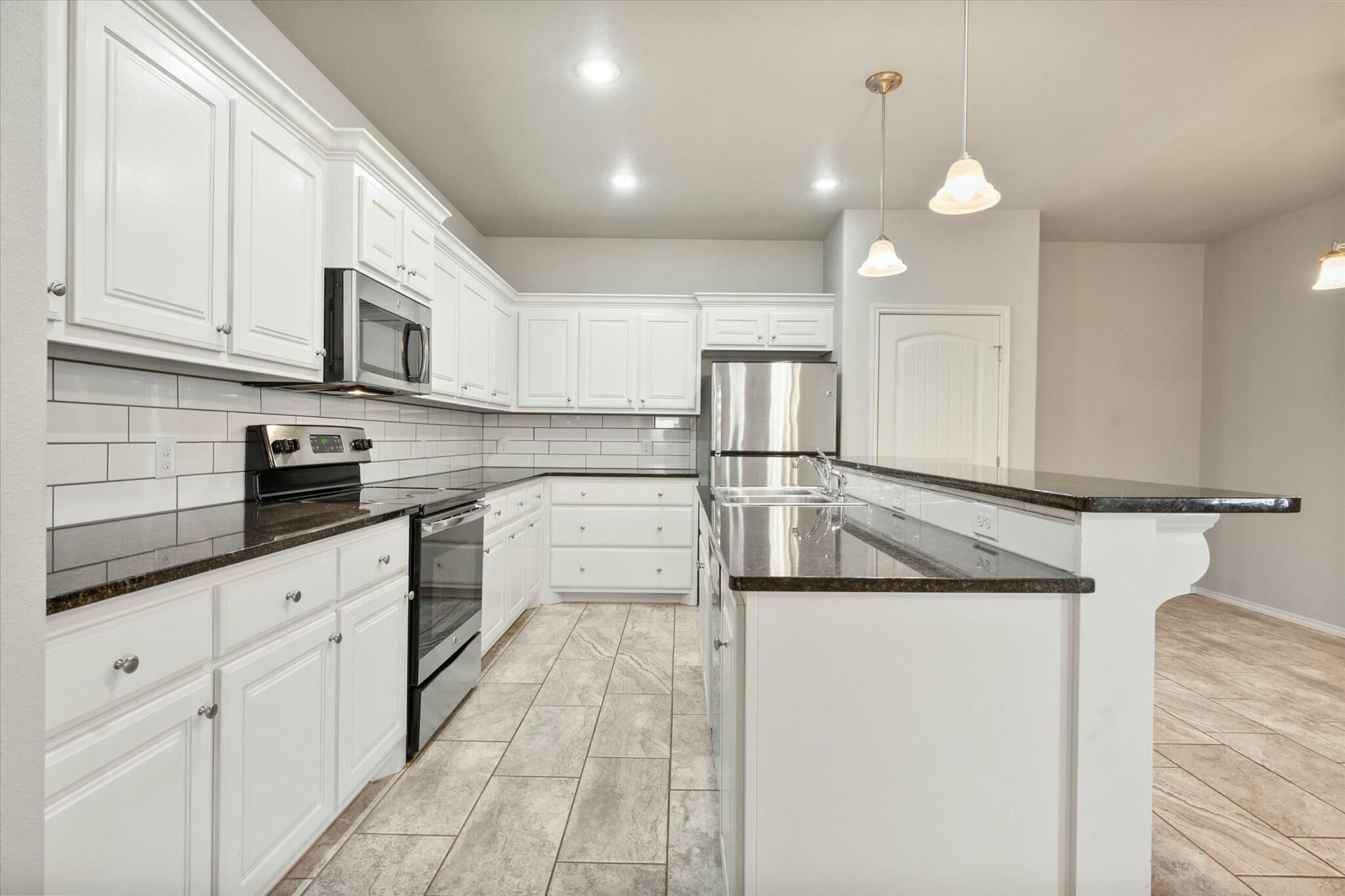 2619 113th Street Lubbock, TX 79423 - Photo 18 of 31 a kitchen with stainless steel appliances granite countertop a sink and white cabinets