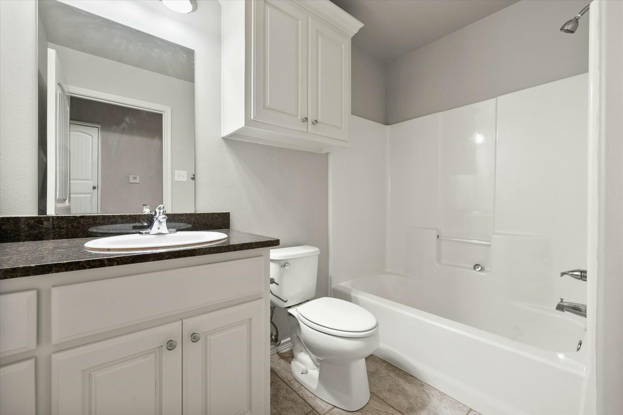 2619 113th Street Lubbock, TX 79423 - Photo 20 of 31 a bathroom with a granite countertop sink a toilet and bathtub