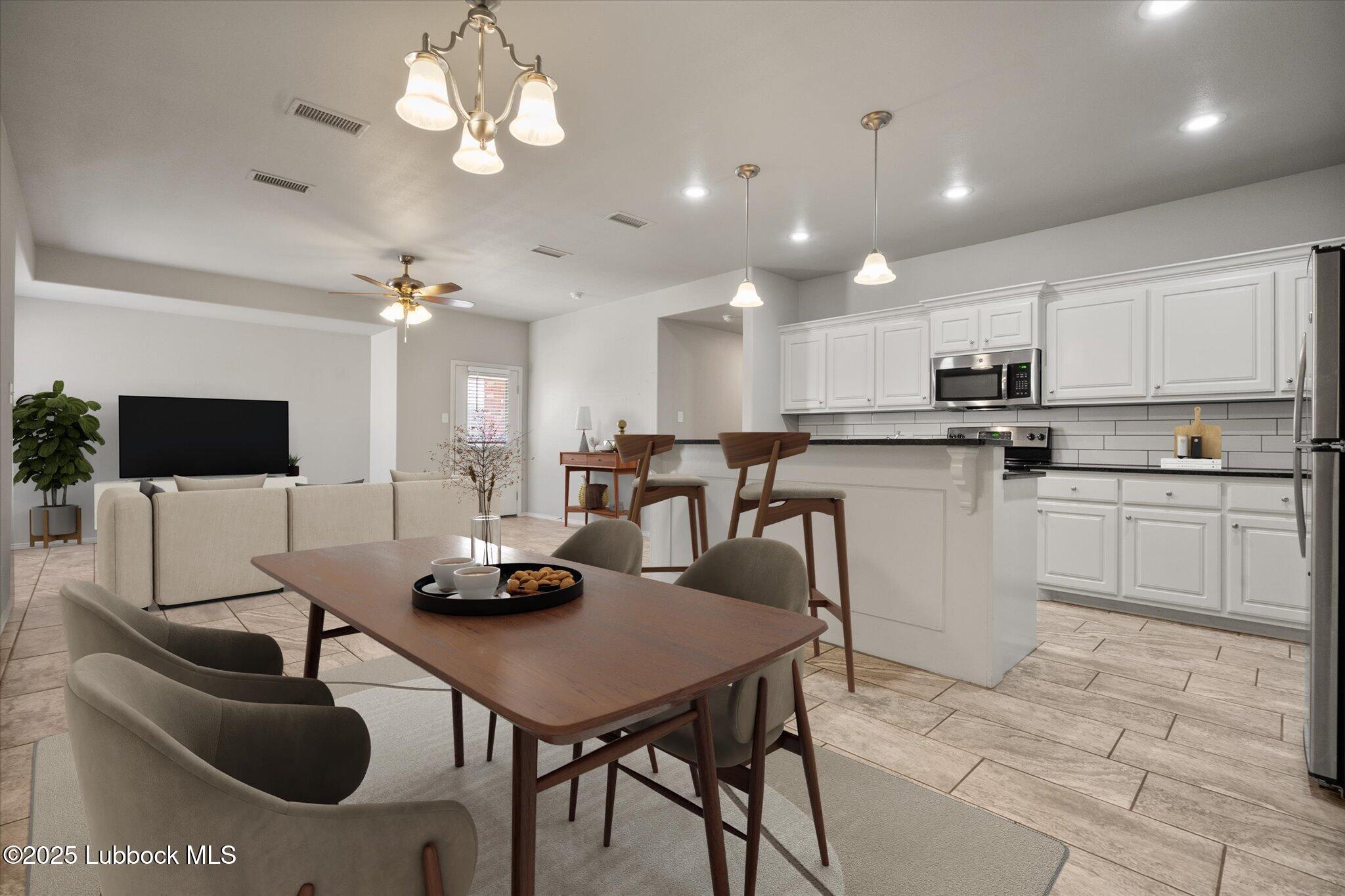 2619 113th Street Lubbock, TX 79423 - Photo 9 of 31 a kitchen with stainless steel appliances kitchen island granite countertop a sink a stove a dining table and chairs