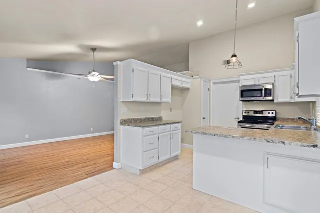 a kitchen with kitchen island granite countertop a sink a stove a refrigerator and white cabinets