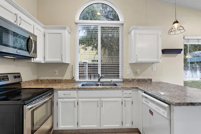 a kitchen with stainless steel appliances granite countertop a stove a sink and a microwave