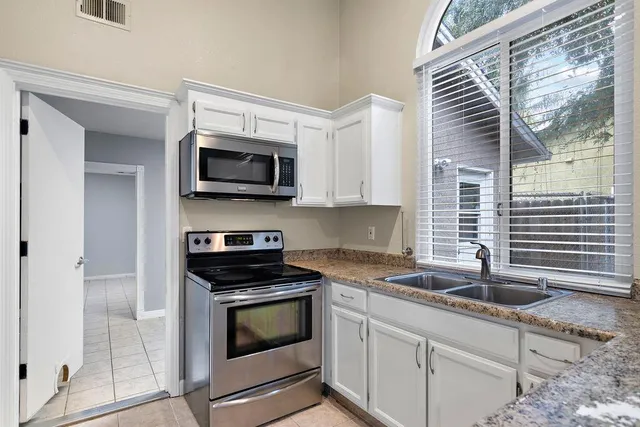 a kitchen with granite countertop a stove a sink and a microwave