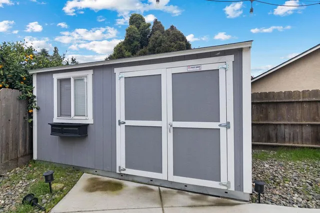 a view of backyard with large tree and wooden fence