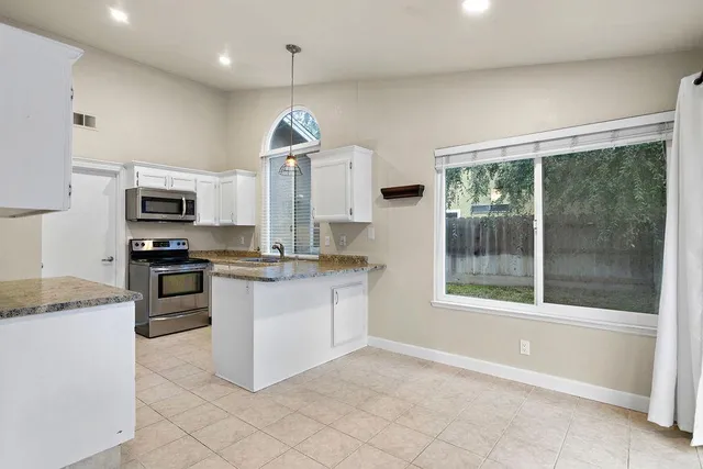 a kitchen with granite countertop a stove a sink and a refrigerator