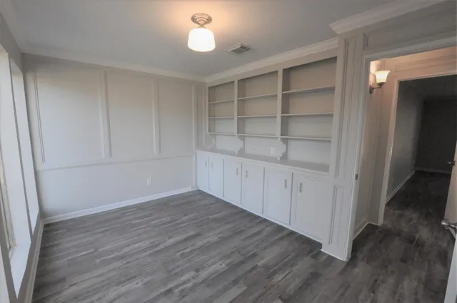 a view of an empty room with wooden floor and closet