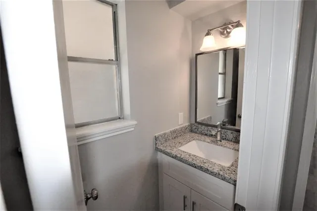 a bathroom with a granite countertop sink and a mirror