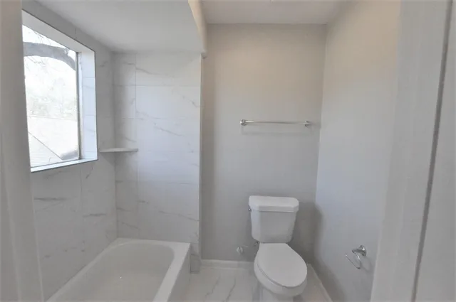 a white toilet sitting next to a bath tub