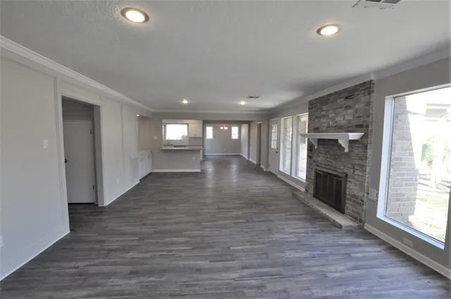 an empty room with wooden floor fireplace and windows