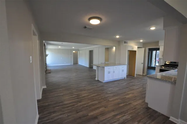 a view of a big room with wooden floor and a kitchen