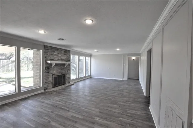 an empty room with wooden floor fireplace and windows