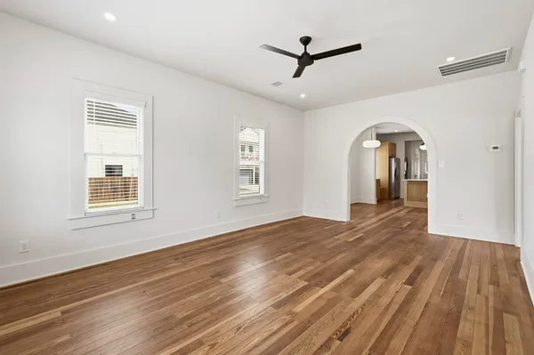 a view of empty room with wooden floor and fan