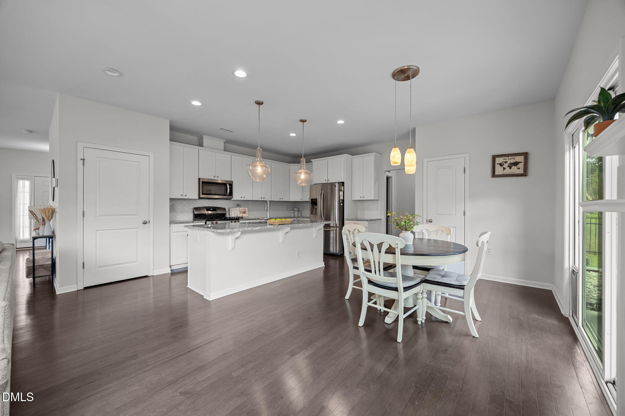 1525 Reynolds Mill Road Wake Forest, NC 27587 - Photo 14 of 40 a kitchen with stainless steel appliances kitchen island granite countertop a dining table chairs and white cabinets