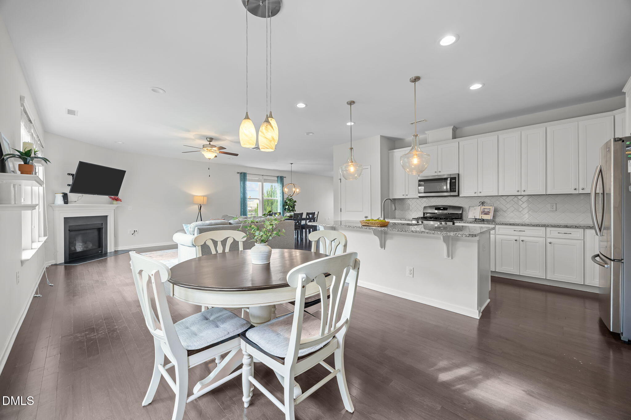 1525 Reynolds Mill Road Wake Forest, NC 27587 - Photo 19 of 40 a dining room with kitchen island furniture a fireplace and a kitchen view