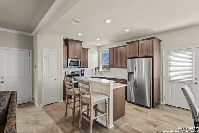 a kitchen with kitchen island a refrigerator and a stove top oven