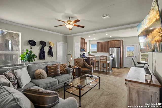 a living room with furniture kitchen view and a large window
