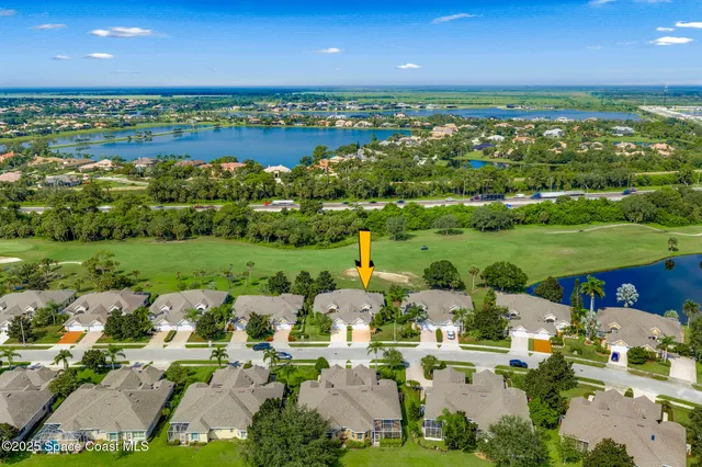 an aerial view of a house with a yard and lawn chairs under an umbrella