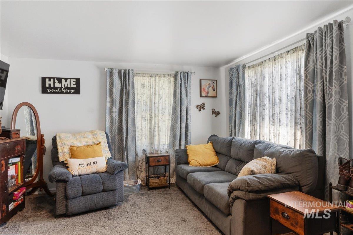 1958 East 1775 South Gooding, ID 83330 - Photo 7 of 49 Living area featuring neutral wall tones, textured carpeting, and multiple windows with layered window treatments