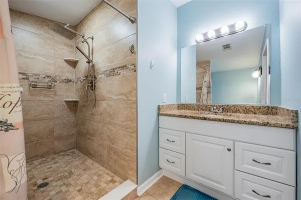 a bathroom with a granite countertop sink a mirror and shower