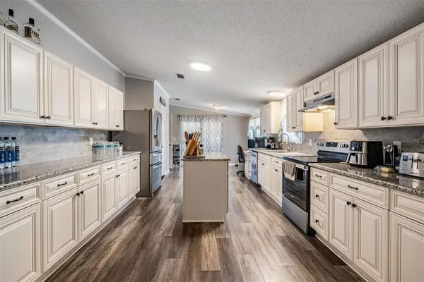 a large kitchen with stainless steel appliances granite countertop a lot of counter space and wooden floors
