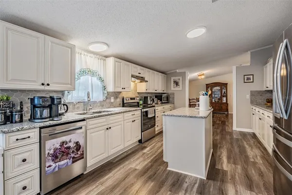 a kitchen with granite countertop a refrigerator stove top oven and sink