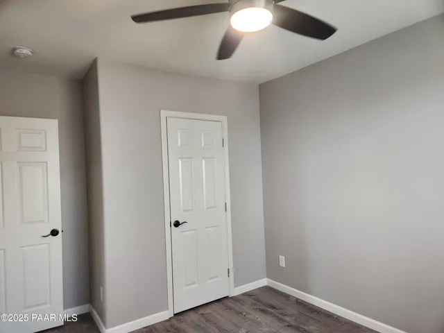 an empty room with wooden floor and a ceiling fan