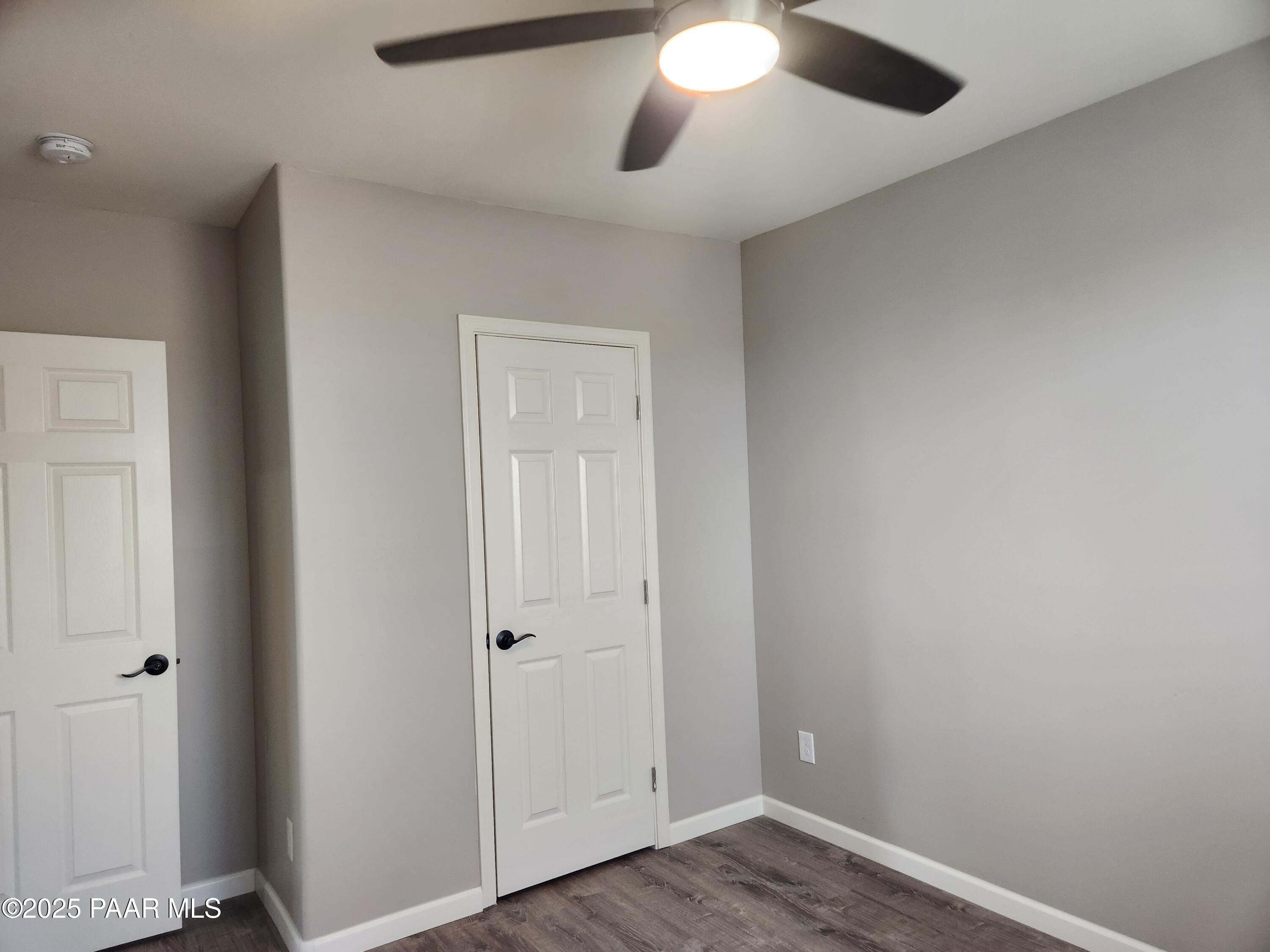 895 Ranch House Road Paulden, AZ 86334 - Photo 11 of 21 an empty room with wooden floor and a ceiling fan