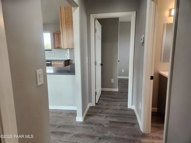a view of a hallway with wooden floor cabinets and a kitchen