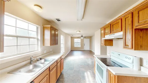 an empty room with wooden floor fan and windows